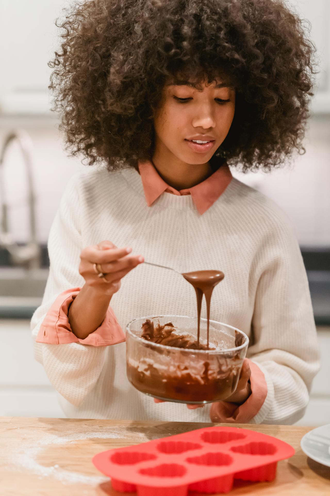 woman scoopign chocolate into silicone tray